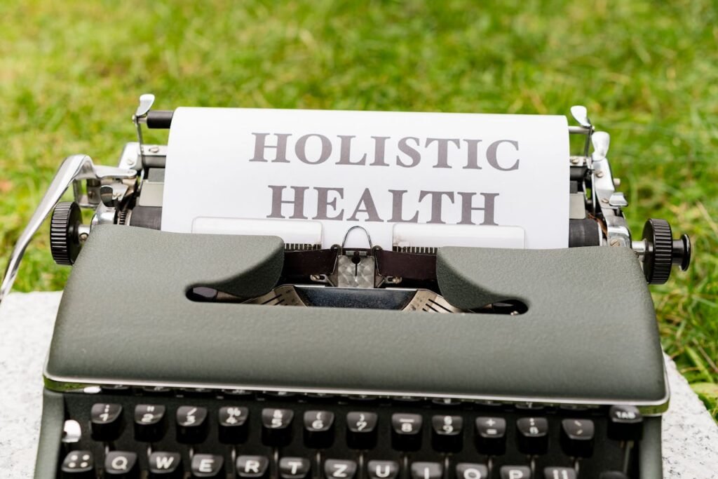pexels-photo-18485506 A vintage typewriter in a grassy outdoor setting displaying 'Holistic Health' on paper.